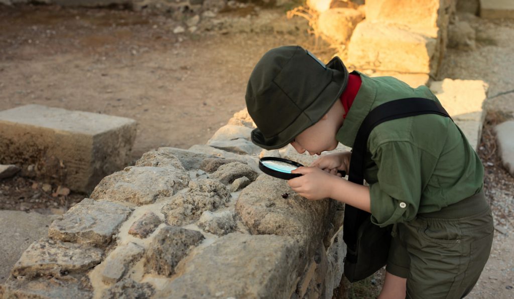Boy archaeologist in khaki clothes studying the ruins of an ancient city 