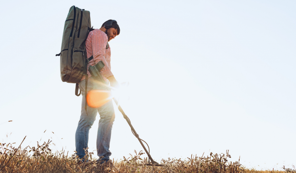 Man with metal detector equipment searching for metal goods in the field