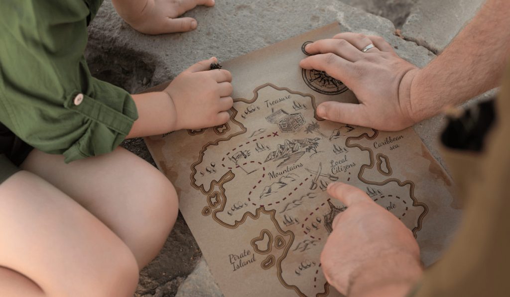 Two archeologists, child and adult, in khaki clothes sitting on the ruins and studying ancient map 