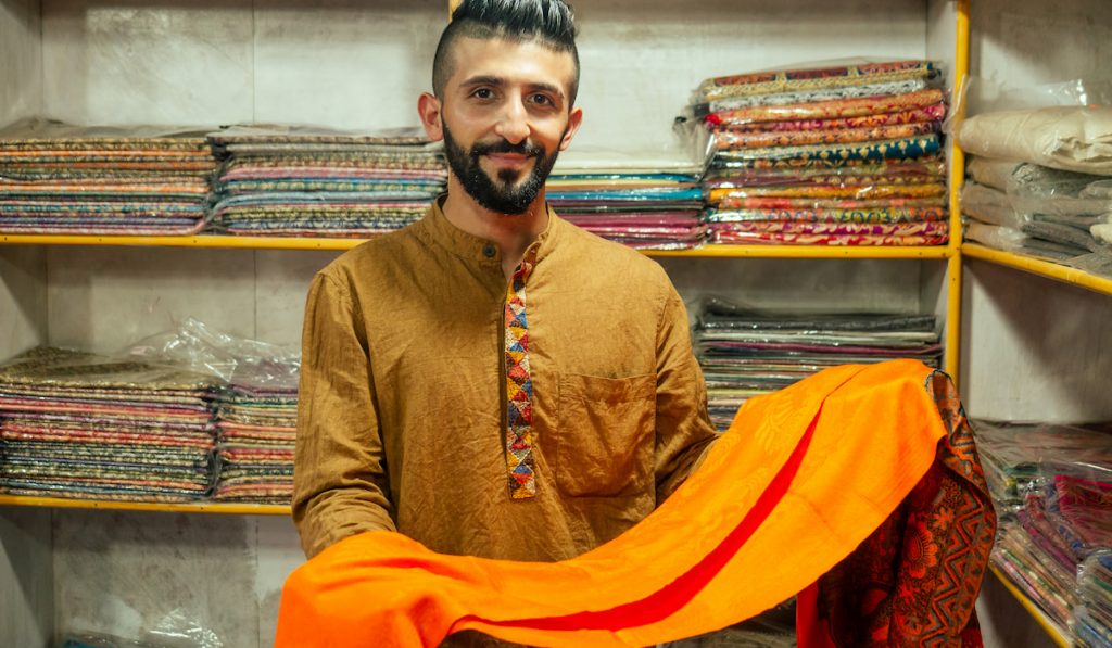 egyptian man shop owner promoting shawls at his store