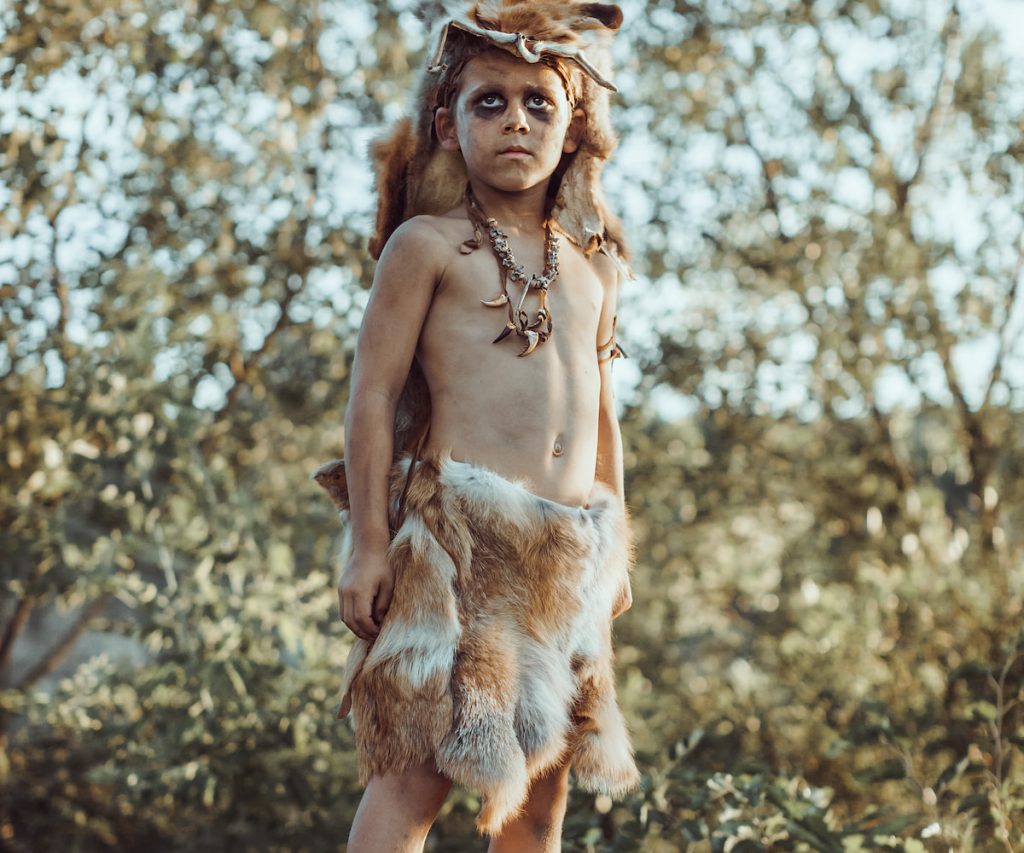 little boy wearing animal skin as clothing ancient prehistoric warrior 