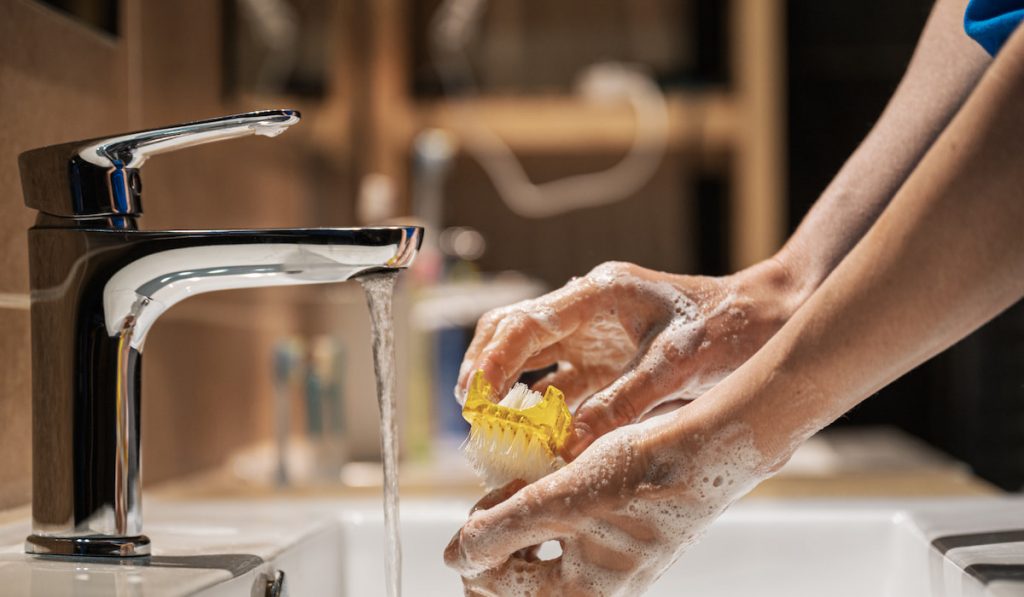 Closeup view of a woman washing her hands with soap and brush
