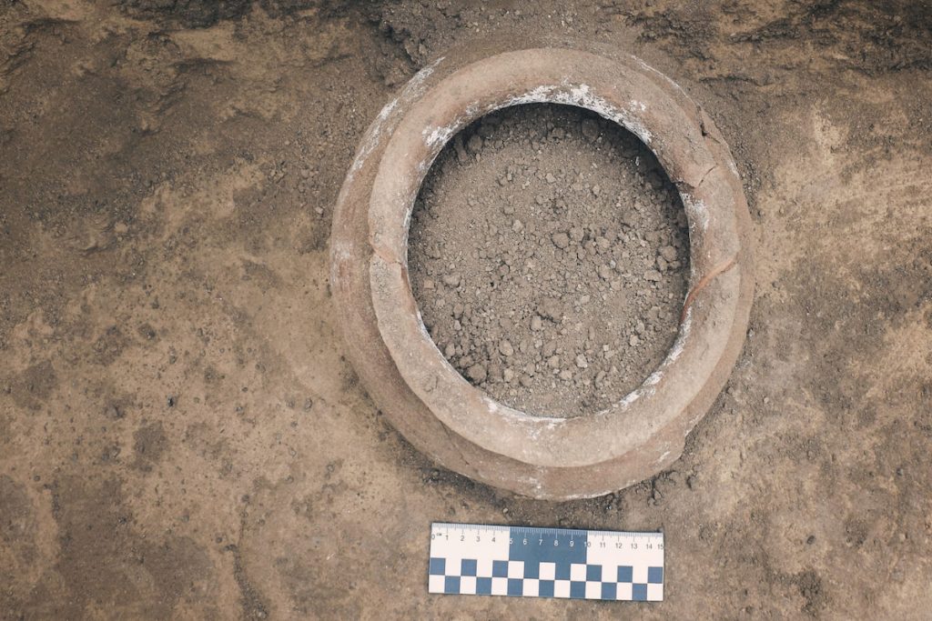 top view of a ceramic jug, pot in a burial, discovered during archaeological excavations, with a scale ruler